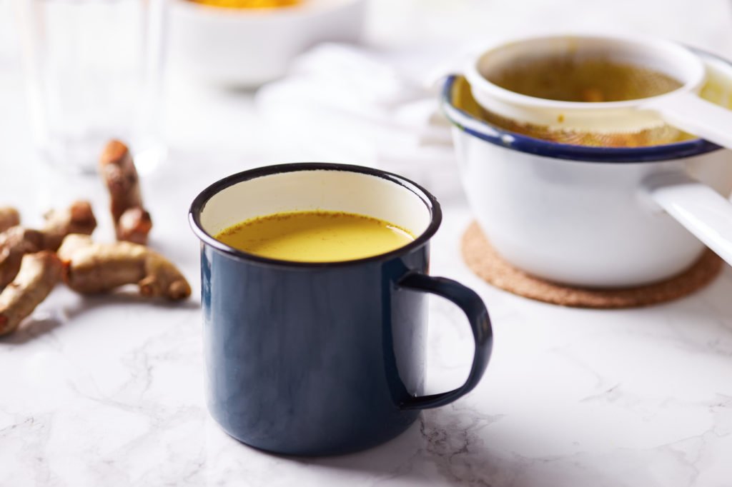 Healthy turmeric drink in blue mug on table